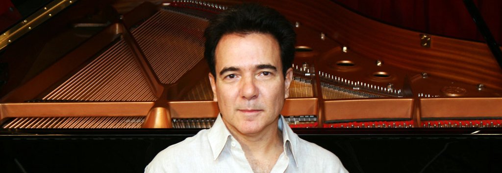 O pianista Luciano Alves com piano ao fundo.